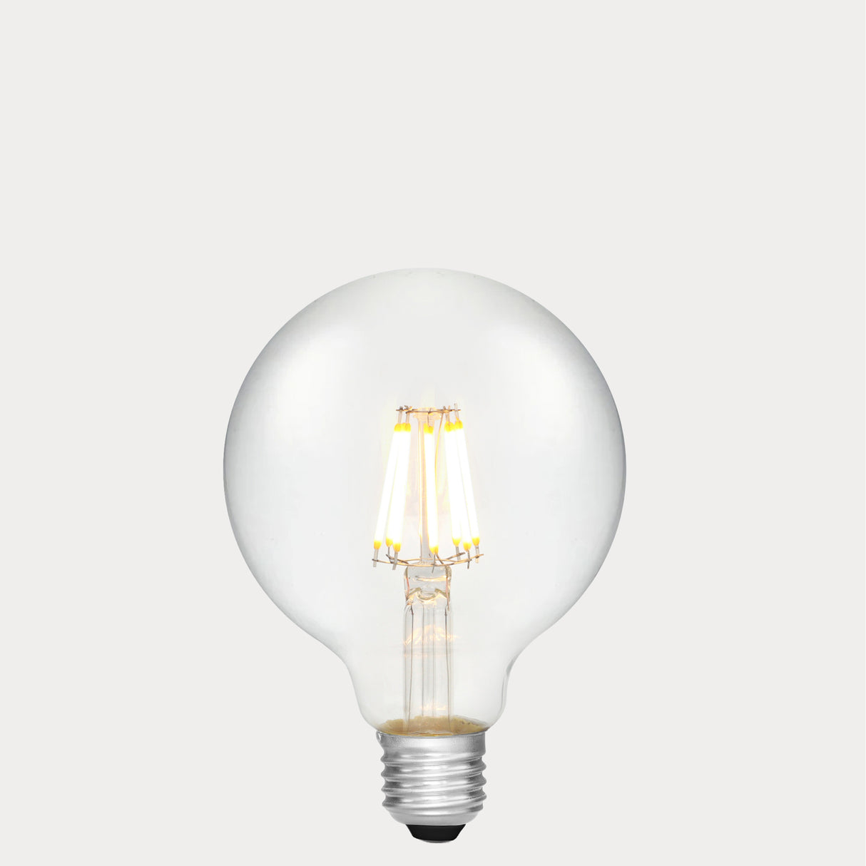 Dulora 8W E27 LED globe bulb in clear glass with AC/DC compatibility, glowing with 2700K warm white light.