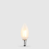 The Liquid LEDs 4W 24 Volt DC Candle LED Bulb E14 Frost in Warm White glows softly with a dimmable, frosted finish against a light gray background.