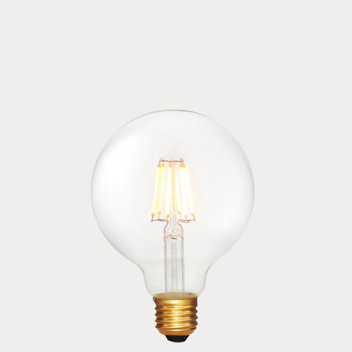 Dulora 6W E27 LED globe bulb in clear glass with 24V compatibility, glowing with 2200K extra warm white light.