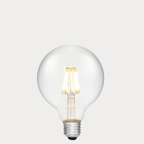 Dulora 8W E27 LED globe bulb in clear glass with AC/DC compatibility, glowing with 2700K warm white light.
